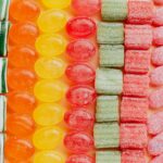 From above of various delicious jelly and caramel sweets arranged in rows by type and color in modern candy store