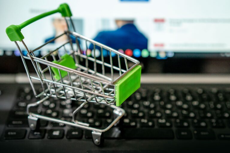 Miniature shopping cart on a laptop keyboard symbolizing abandoned cart recovery for e-commerce