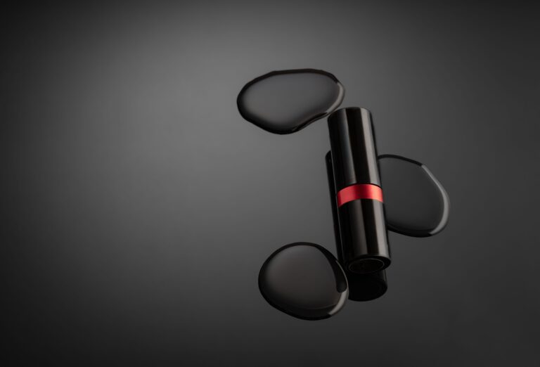Studio product photography shot of a lipstick with water droplets on a dark background