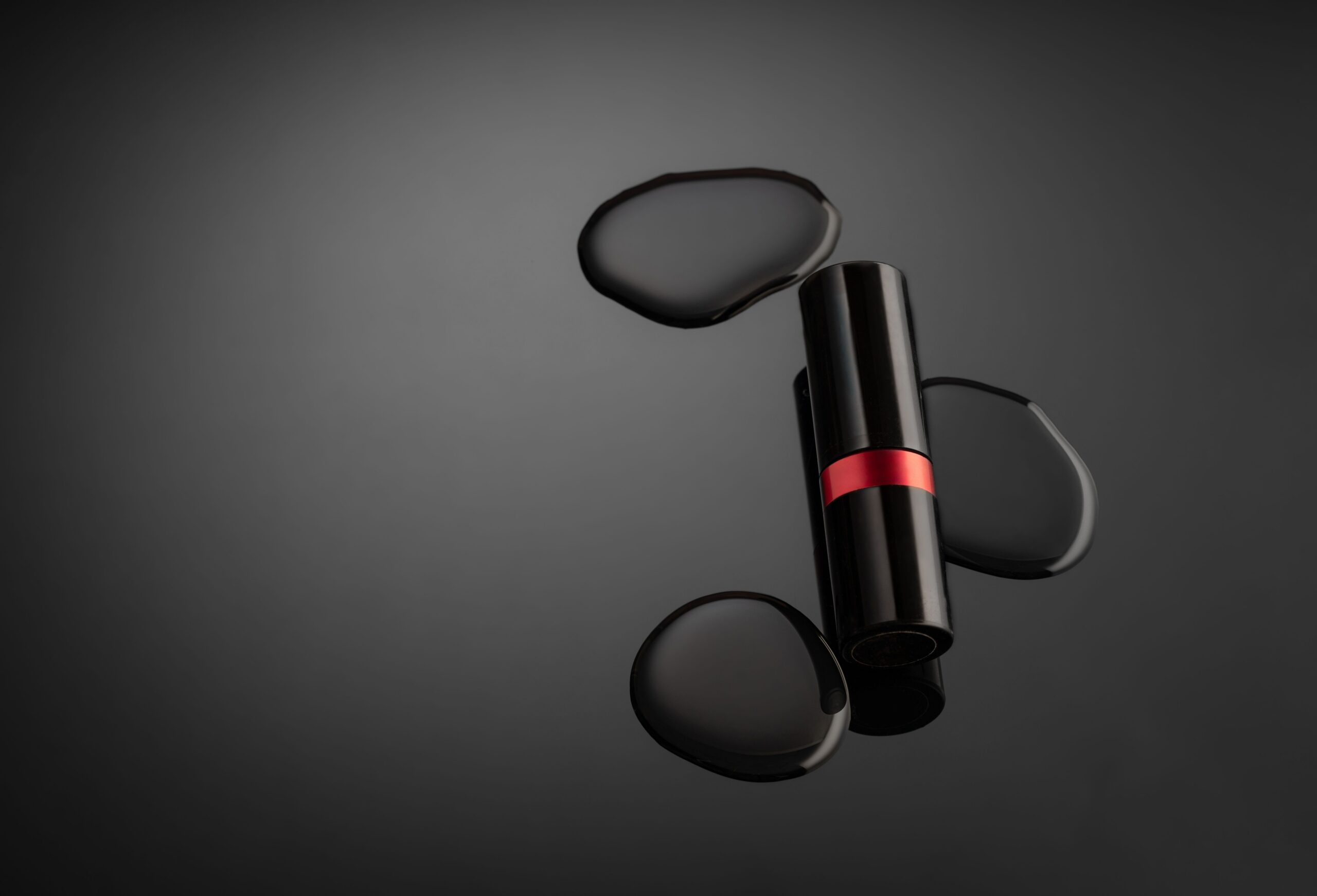 Studio product photography shot of a lipstick with water droplets on a dark background