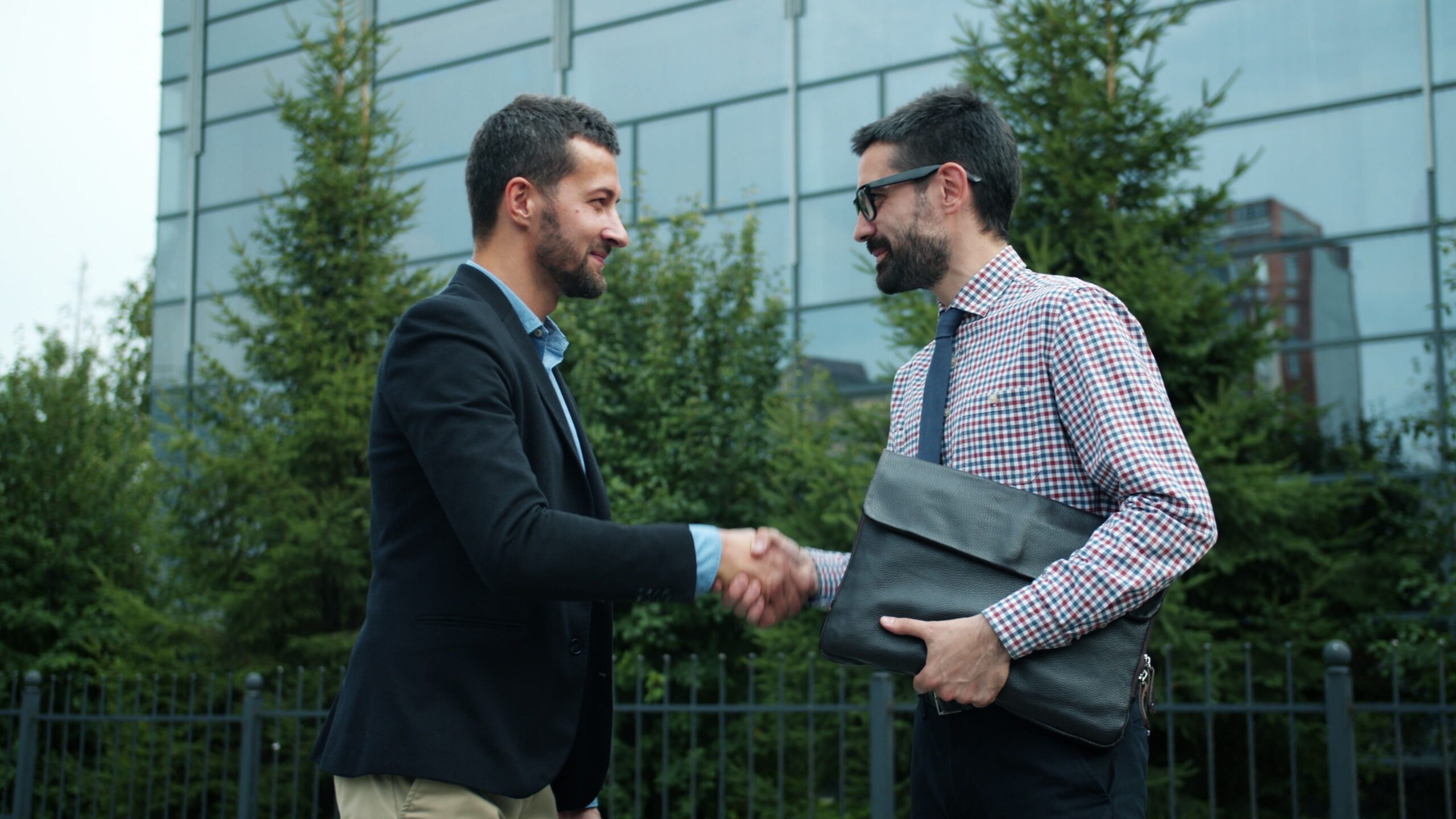 Two businessmen shaking hands outside a modern office building