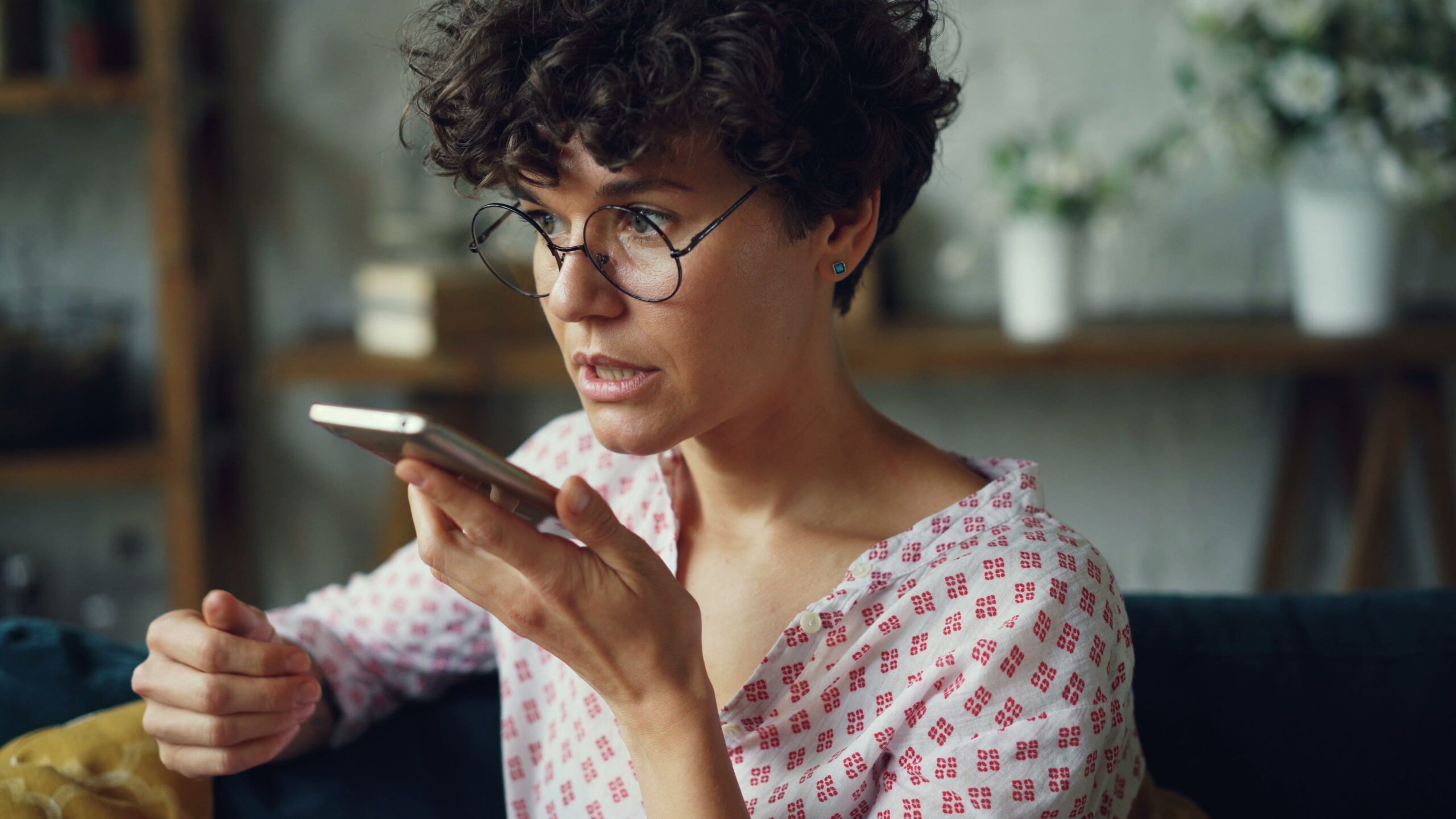 Casual woman using AI voice command on smartphone at home