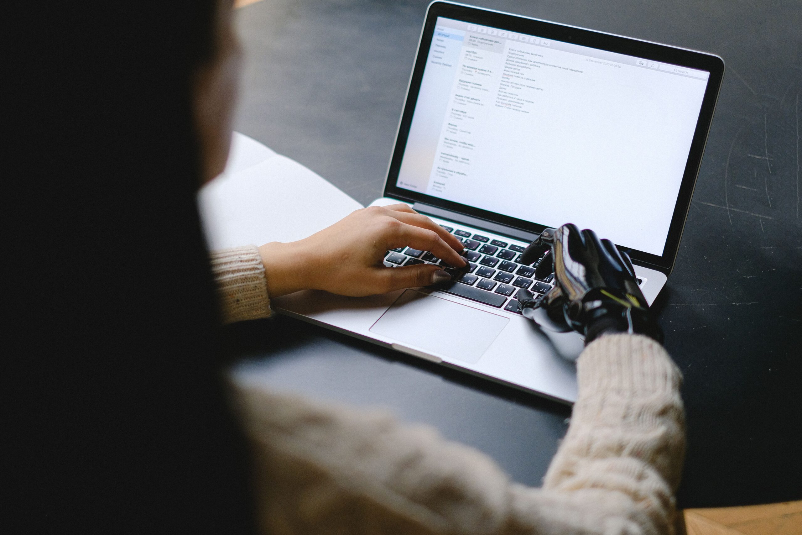 Person with a prosthetic hand using a laptop, representing web accessibility and inclusive design for small business websites