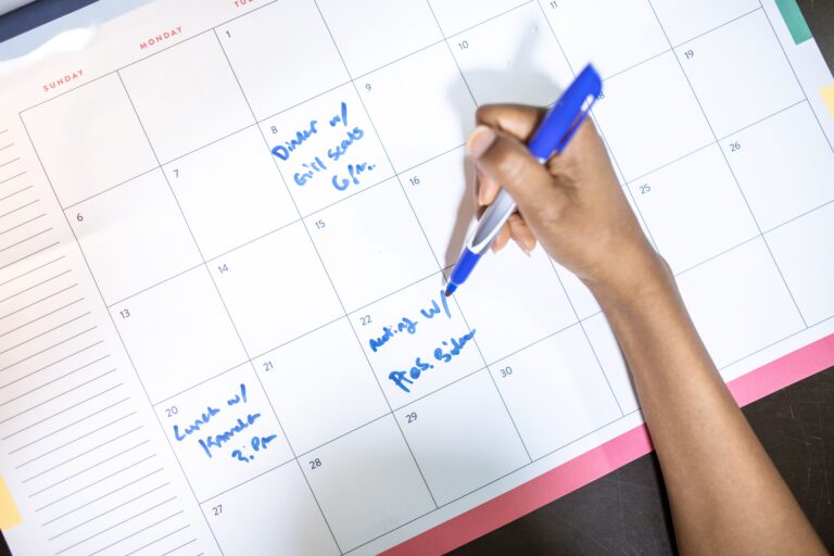 Person writing appointments on a desk calendar for online booking and scheduling