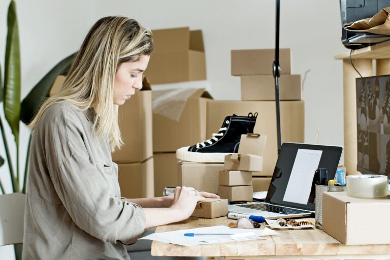 Small business owner packing boxes for an online store surrounded by packaging materials