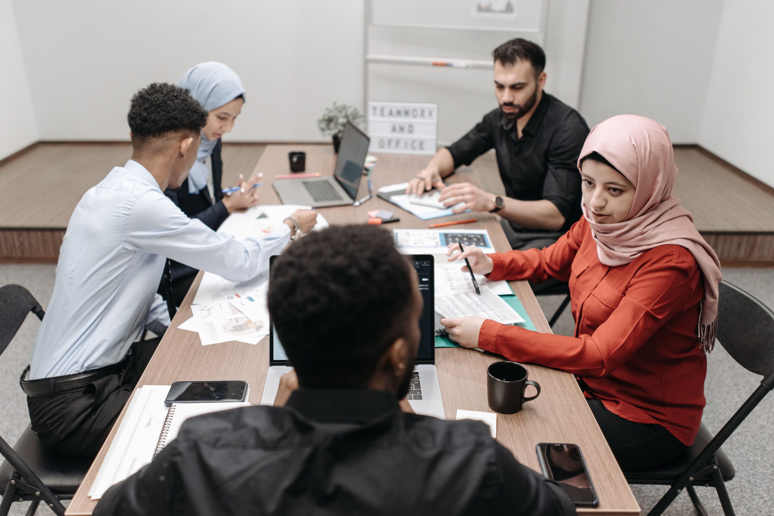 Too many meetings at work: a small team in a meeting at the office, meeting overload cost small business