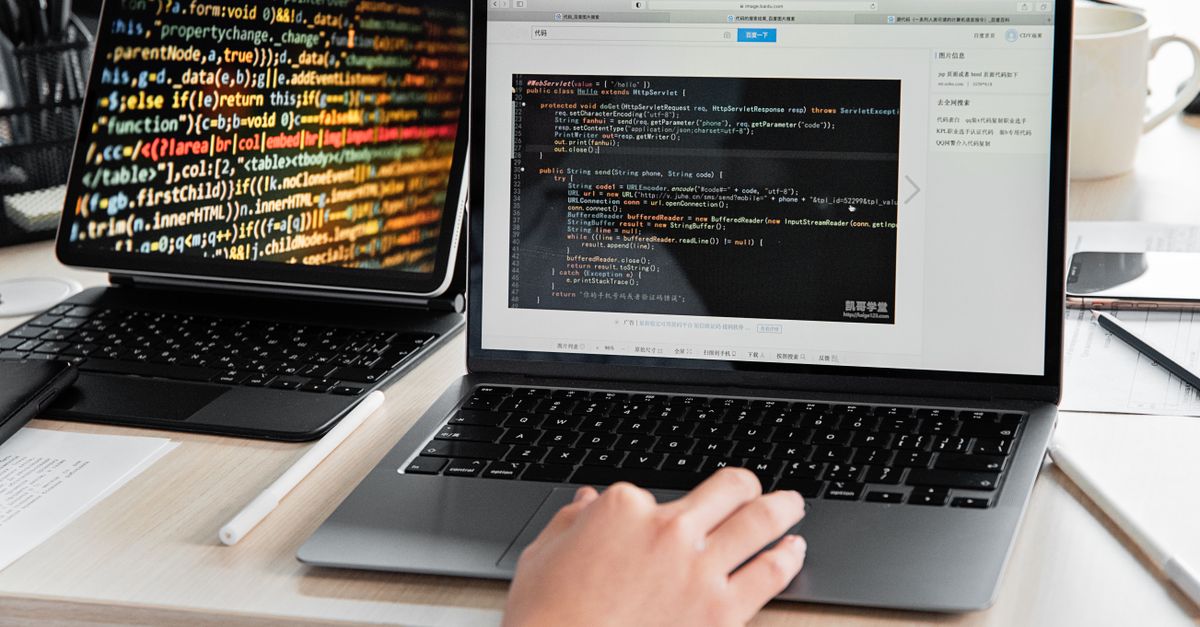 A developer writing code on a laptop, displaying programming scripts in an office environment.